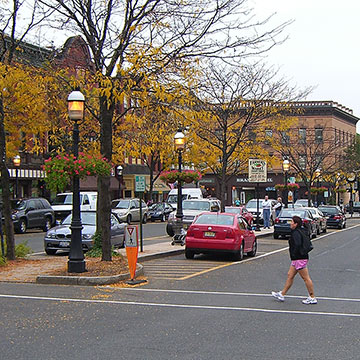 Downtown refuge island. Woman crossing a street in crosswalk.